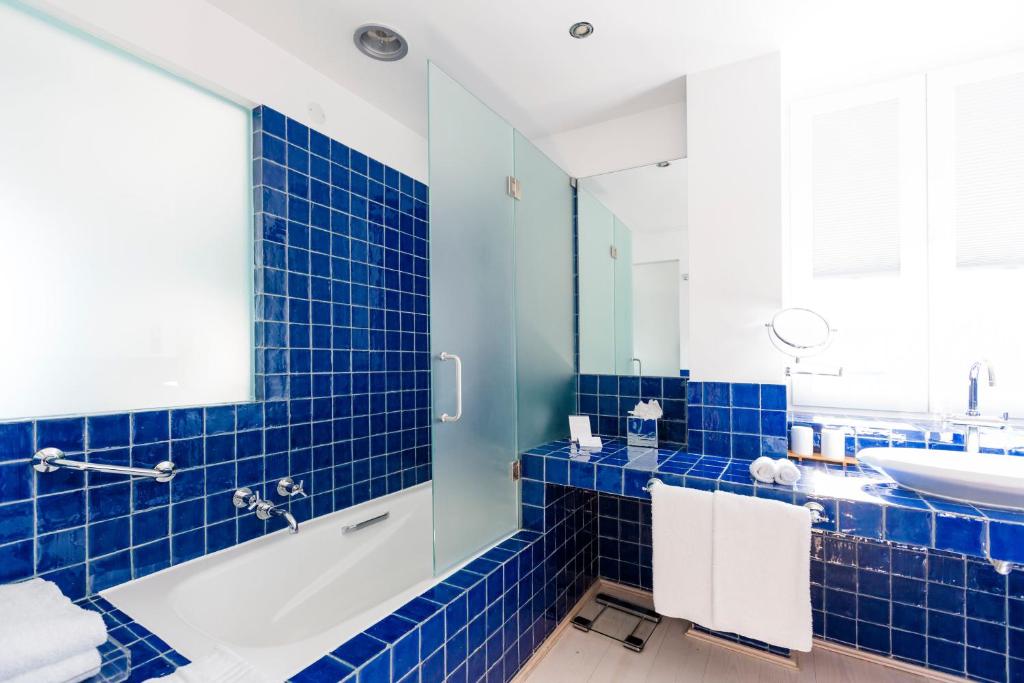 a blue tiled bathroom with a tub and a sink at The Albatroz Hotel in Cascais