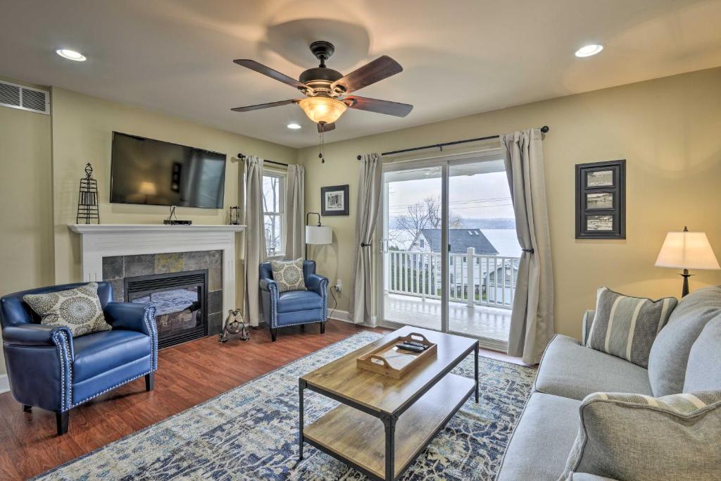 a living room with a fireplace and a ceiling fan at Canandaigua Lake House with Lake View and Fire Pit! in Rushville