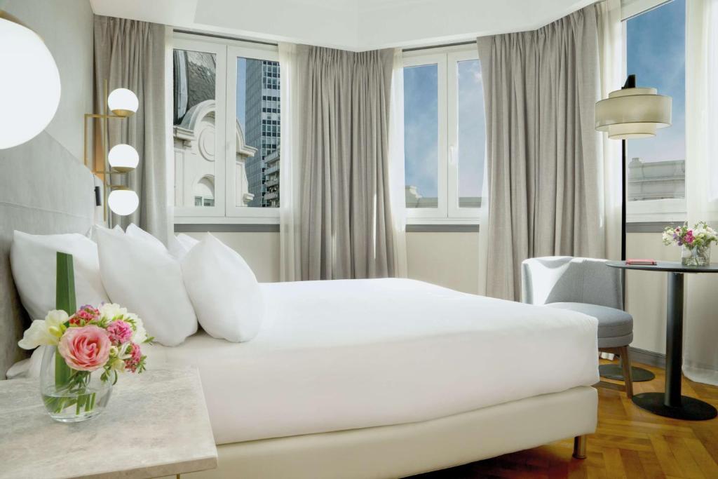a white bedroom with a white bed and a table at NH Collection Buenos Aires Crillón in Buenos Aires