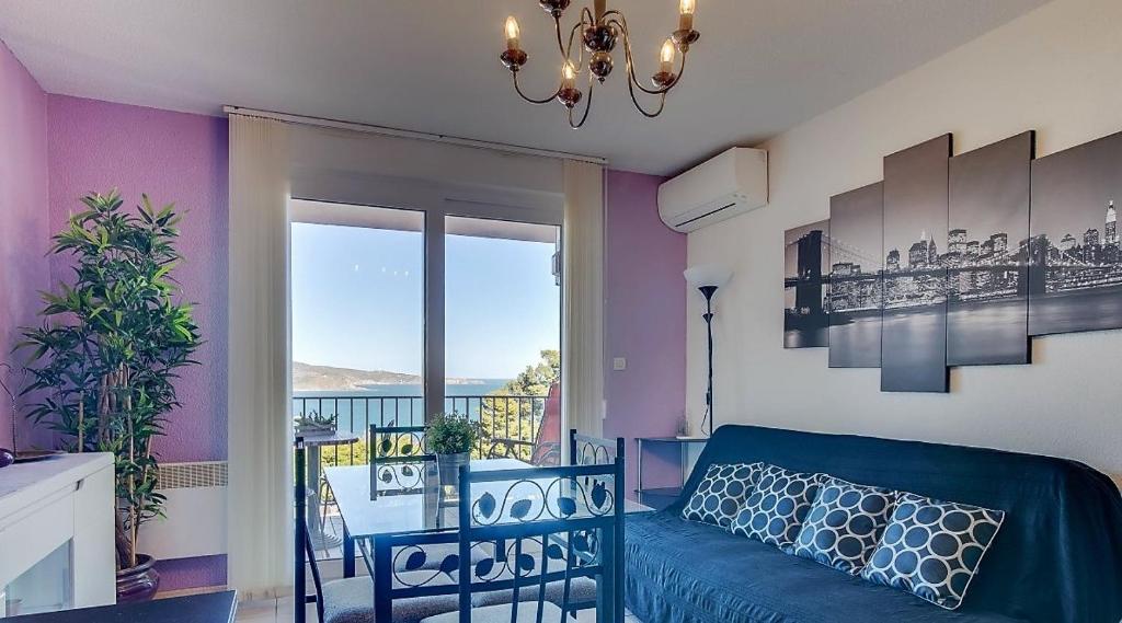 un soggiorno con divano blu e balcone di T 2 tout confort avec terrasse vue mer et montagne. a Banyuls-sur-Mer