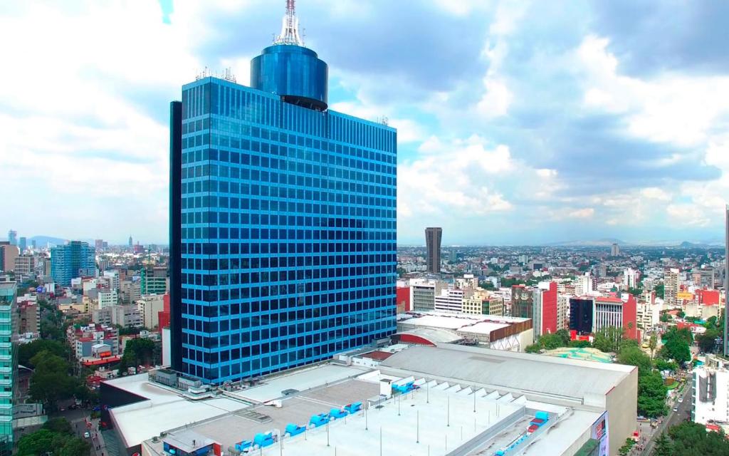 a tall blue building in the middle of a city at izZzleep WTC Mexico (world trade center Mexico) in Mexico City