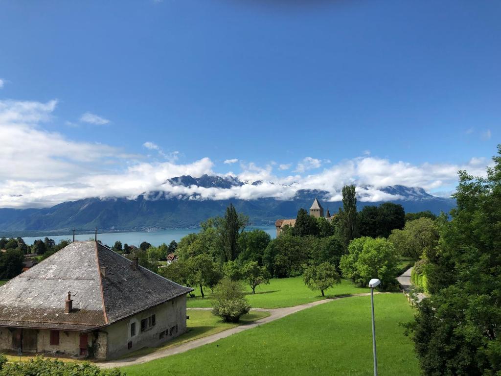 una vecchia casa in un parco con montagne sullo sfondo di La Maison des Copains a Blonay