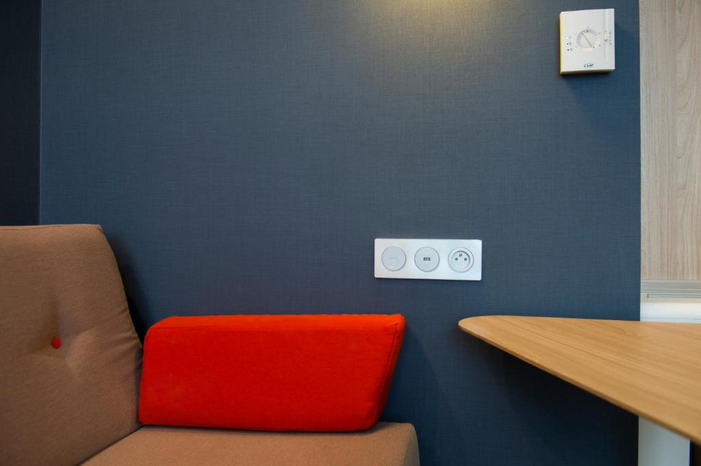 a room with a red chair and a blue wall at Holiday Inn Express - Paris - CDG Airport by IHG in Roissy-en-France