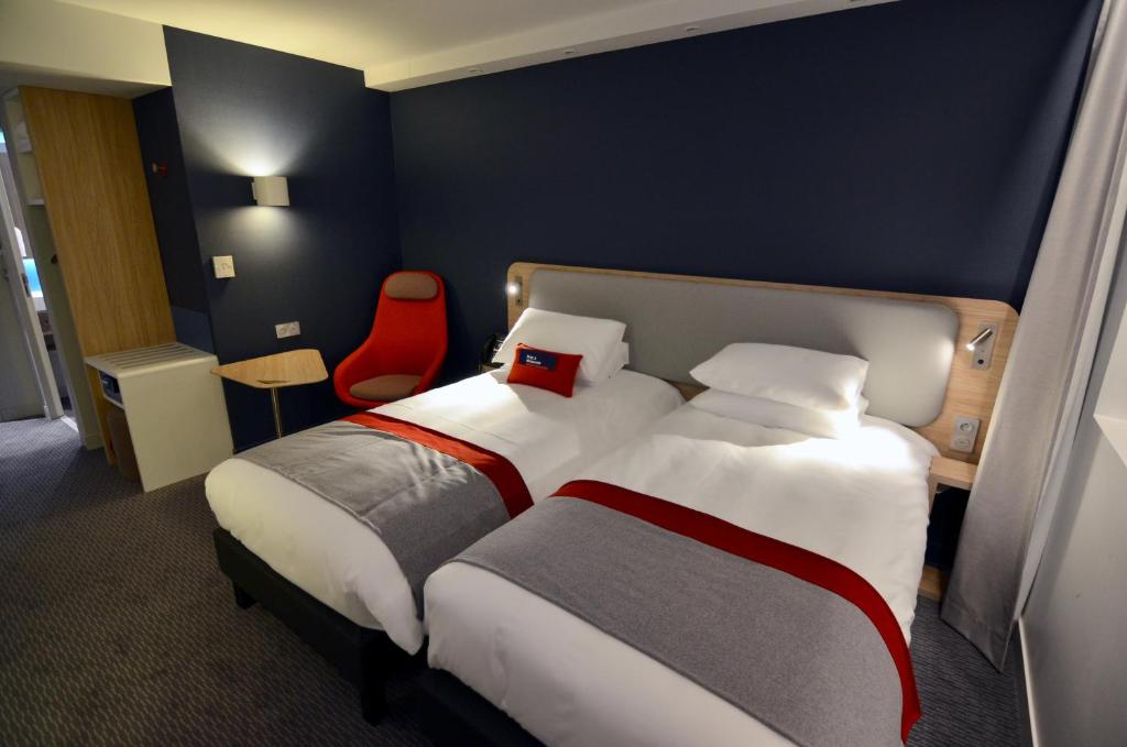 a hotel room with a bed and a red chair at Holiday Inn Express - Paris - CDG Airport by IHG in Roissy-en-France