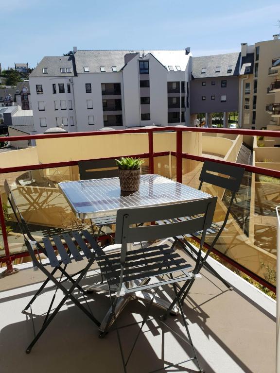 une table et deux chaises sur un balcon dans l'établissement Appartement plage de Trestraou, à Perros-Guirec