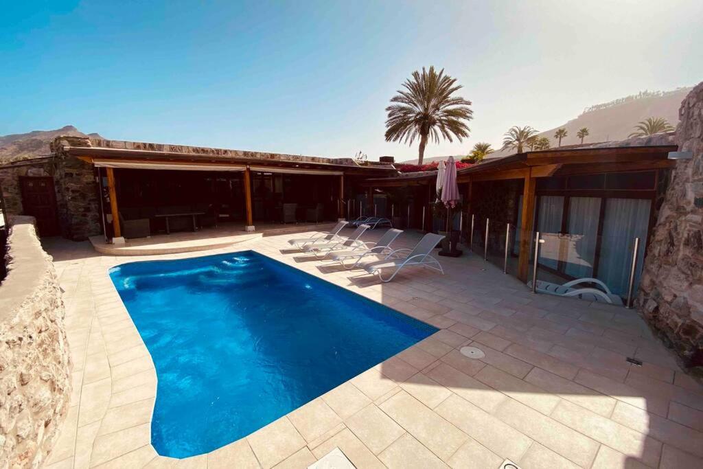 een huis met een zwembad op een patio bij Anfi Tauro Golf Villa with private heated pool in Mogán