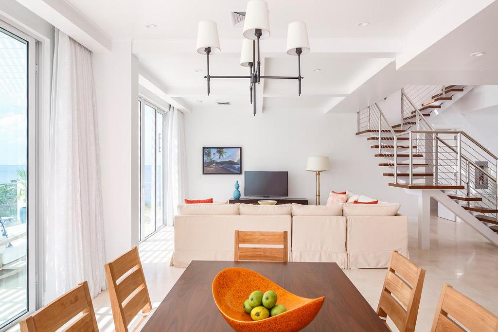 Multi-level suite with dining table, sofa, staircase, ocean-view windows, and modern furnishings.