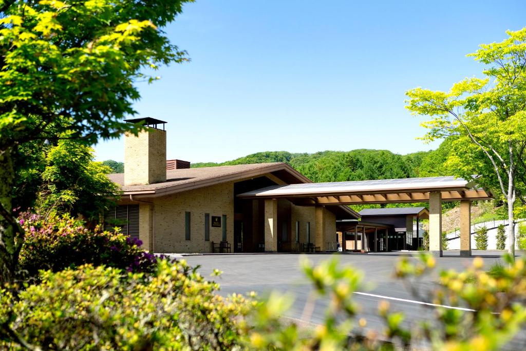 a building with a parking lot and trees at Karuizawa Asama Prince Hotel in Karuizawa