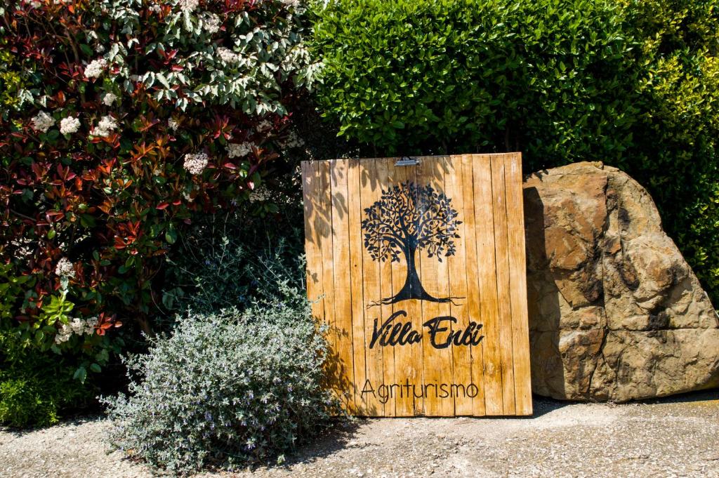 un cartello di legno con un albero sopra, vicino a una roccia. di Villa Enli a Capalbio