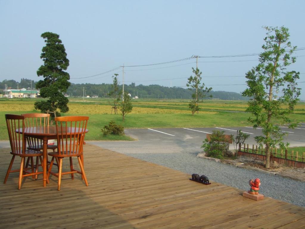 una terraza de madera con 2 sillas y una mesa en Guesthouse Suzukaze, en Shibushi