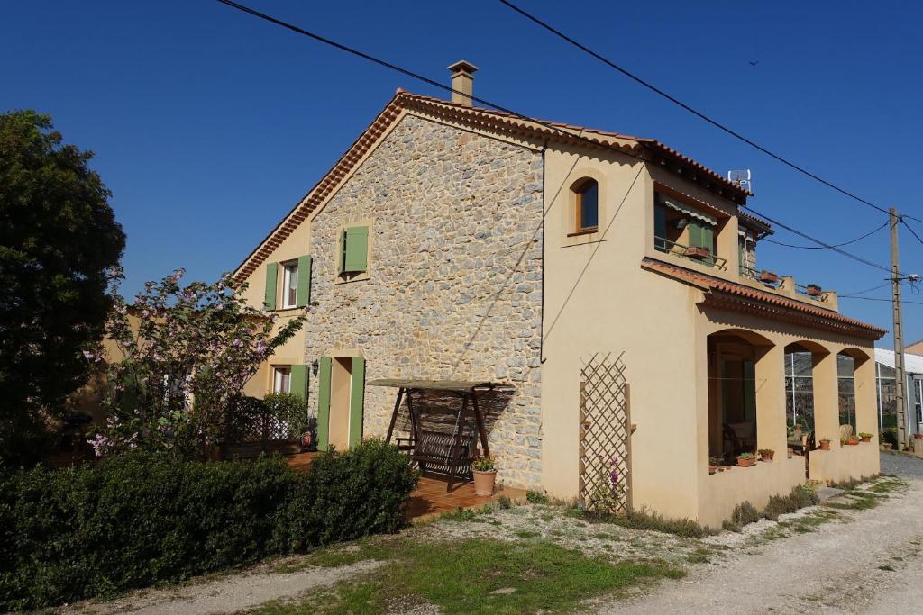 Cette petite maison en pierre dispose de portes vertes et d'une fenêtre. dans l'établissement Gîte du Pagoulin - Chambres d'hôtes, à Hyères