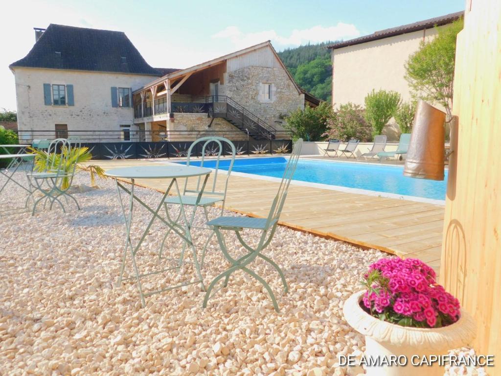 un patio con mesa y sillas junto a una piscina en Le Puits de Garival en Tour-de-Faure