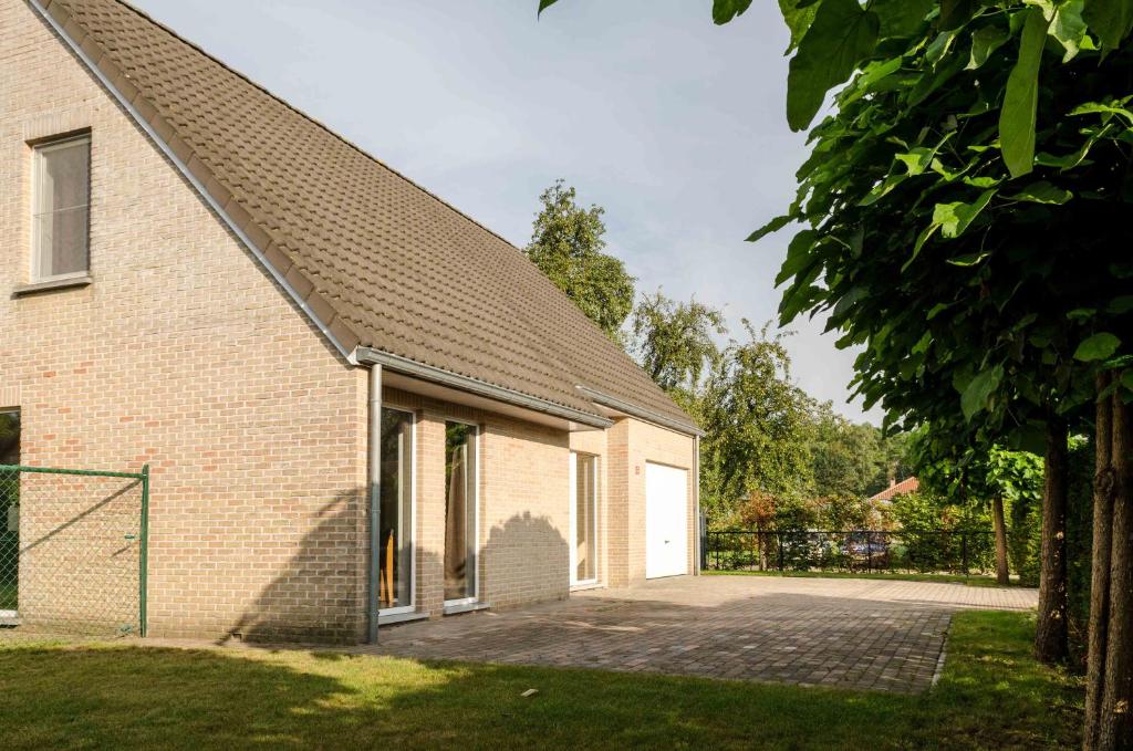 a brick house with a driveway and a white door at De Wilgoren in Kasterlee