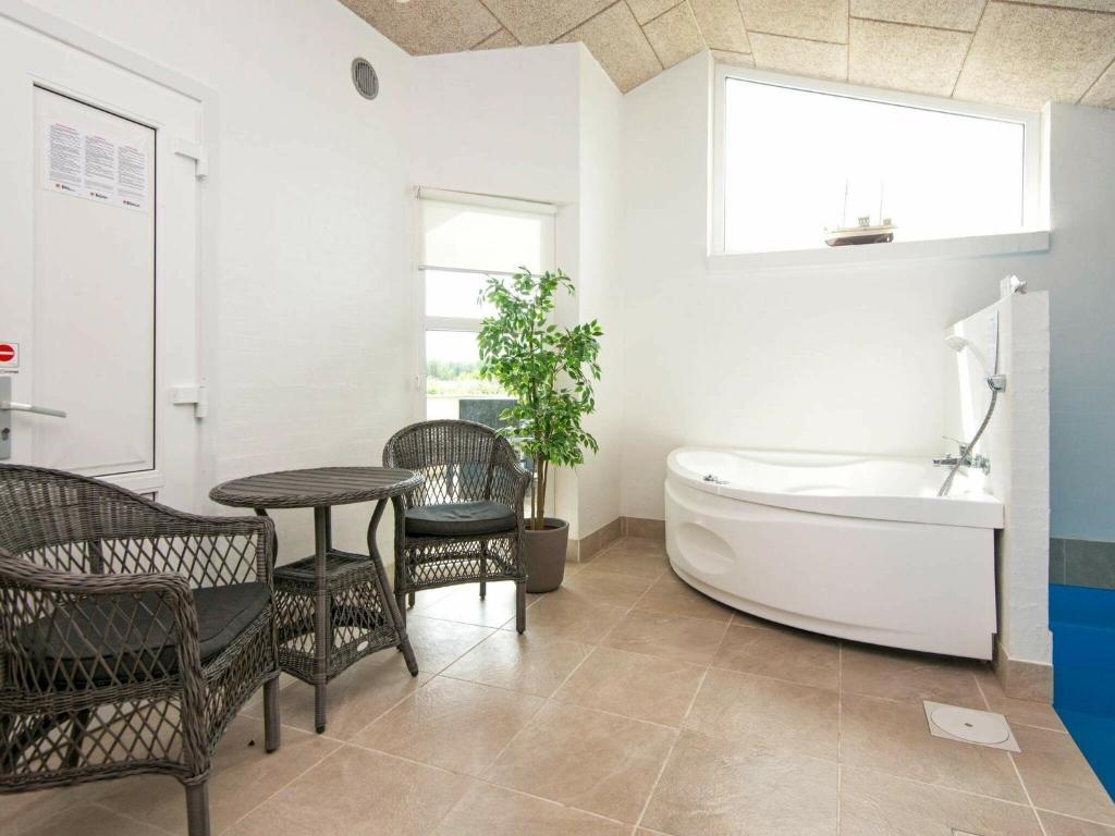 a bathroom with a tub and a table and chairs at Holiday home Juelsminde LIV in Sønderby