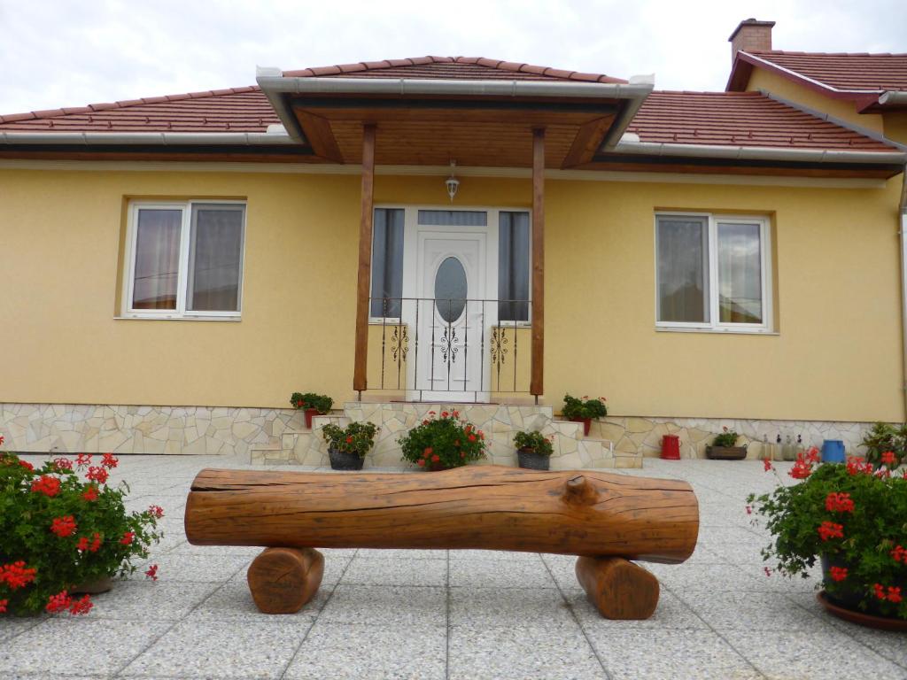 a log bench in front of a house at Napfény Apartman és Vendégház in Egerszalók