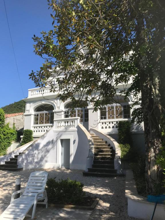 una casa blanca con escaleras y un banco delante en Le Petit Chateau en Puilaurens