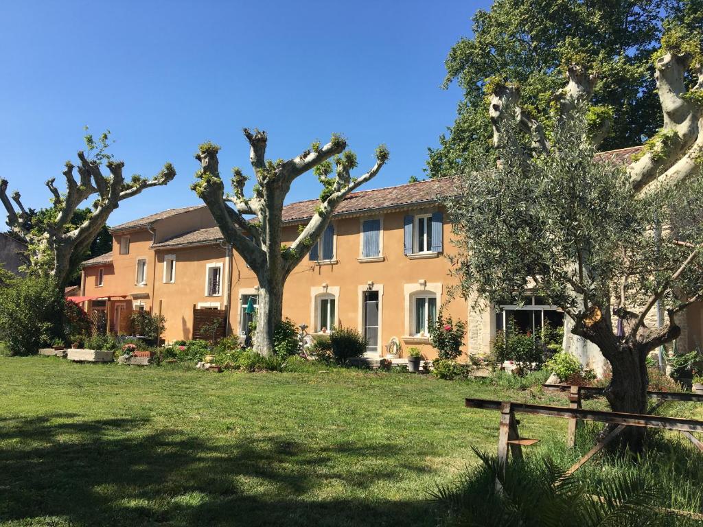 a large yellow house with trees in the yard at Mas Le Nathakassou in Cabannes