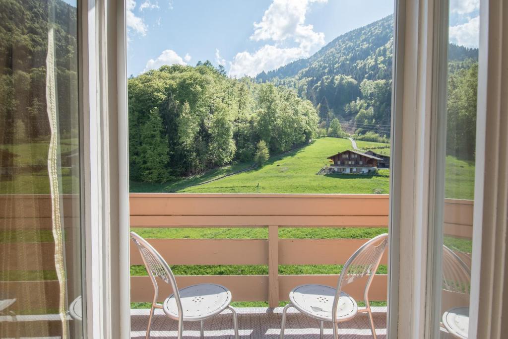a balcony with two chairs and a view of a house at Hotel Berghof Amaranth in Wilderswil