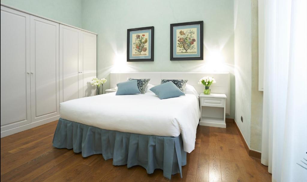 una camera da letto con un grande letto bianco con cuscini blu di B&B La Signoria Di Firenze a Firenze