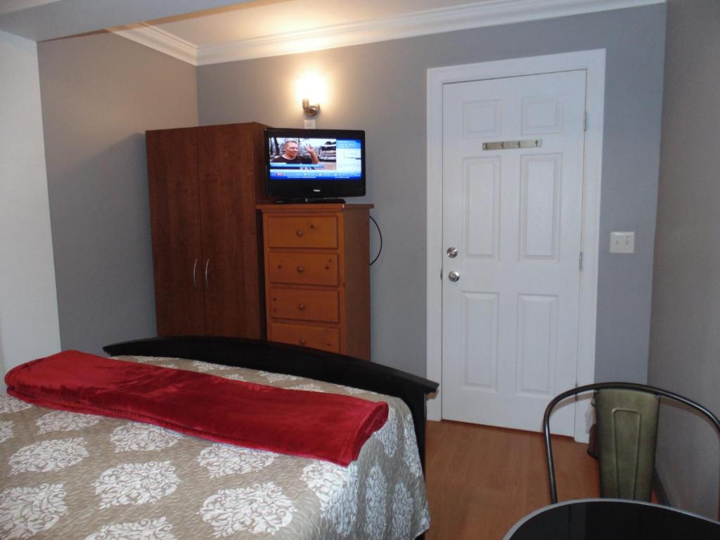 a bedroom with a bed and a television on a dresser at Gordon's Guest House in Vancouver