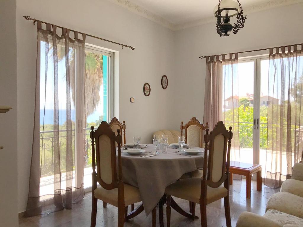comedor con mesa, sillas y ventanas en Kessaris Apartments, en Chrani