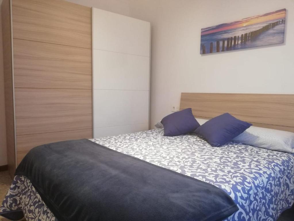 Un dormitorio con una cama con almohadas azules. en Apatamento as xenetas en Marín
