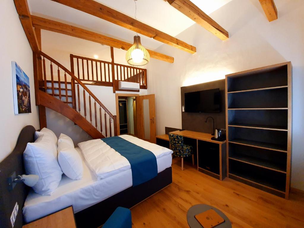 a bedroom with a large bed and a staircase at Hotel KORTUS in Jetřichovice