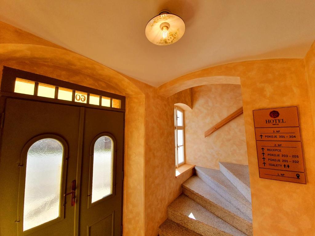 a hallway with a door and stairs in a house at Hotel KORTUS in Jetřichovice