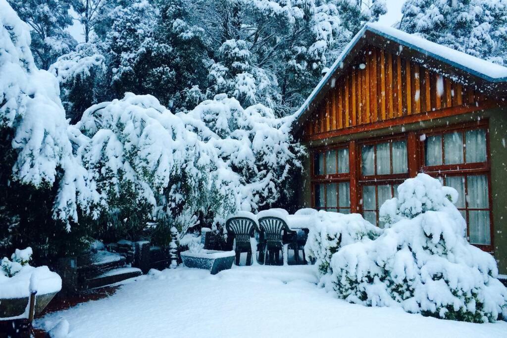 a house covered in snow in front of a cabin at BEAUTIFUL RETREAT - 20 mins to CBD and only 10 mins to MONA! in Collinsvale