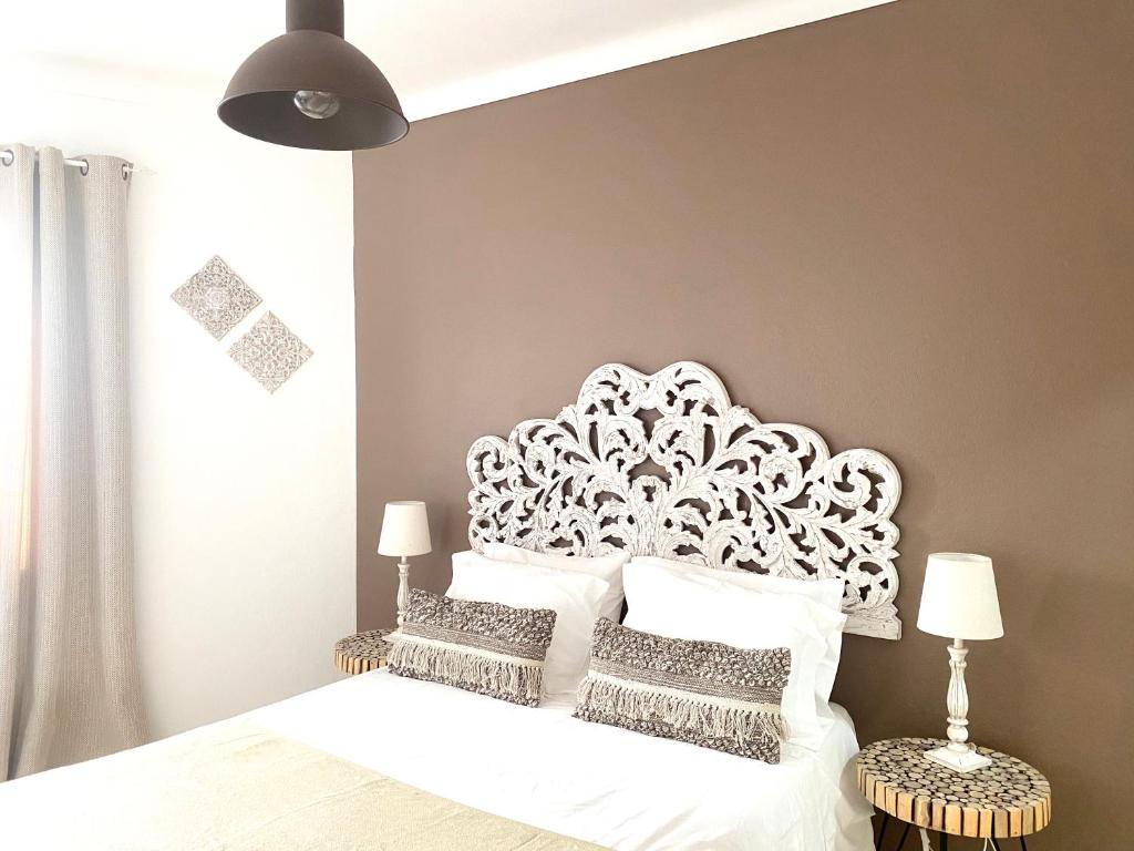 a bedroom with a white bed with a white headboard at Pátio Abílio Guest House in Nazaré