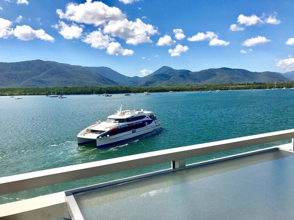Cairns Waterfront Luxury at Harbourlights في كيرنز: قارب على بحيرة وجبال في الخلفية
