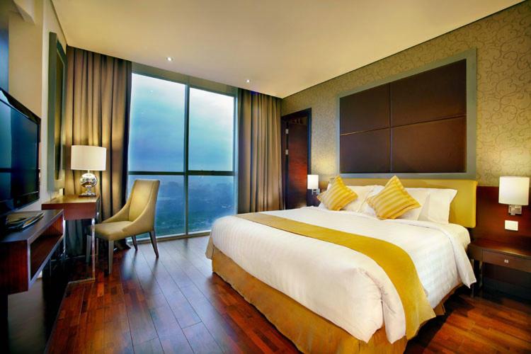 ein Hotelzimmer mit einem großen Bett und einem Schreibtisch in der Unterkunft ASTON Purwokerto Hotel & Conference Center in Purwokerto