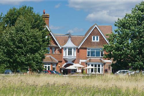 ein großes Backsteinhaus mit davor geparkt in der Unterkunft Hickstead Hotel in Bolney