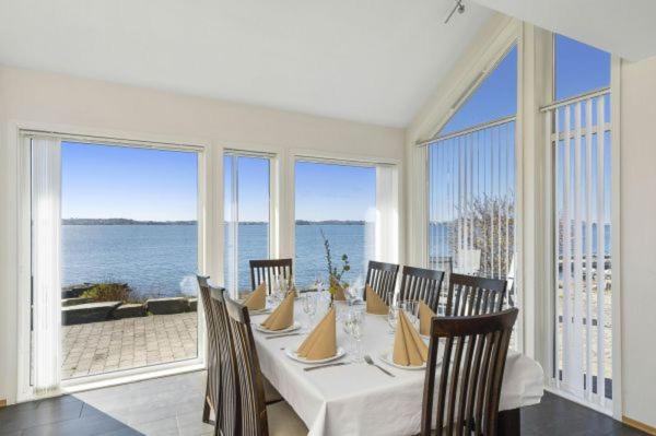 a dining room with a table with chairs and windows at Åmøy Fjordferie in Vestre Amoy