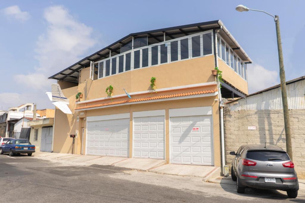 um carro estacionado em frente a um edifício com duas portas de garagem em Euro Hostal em Guatemala