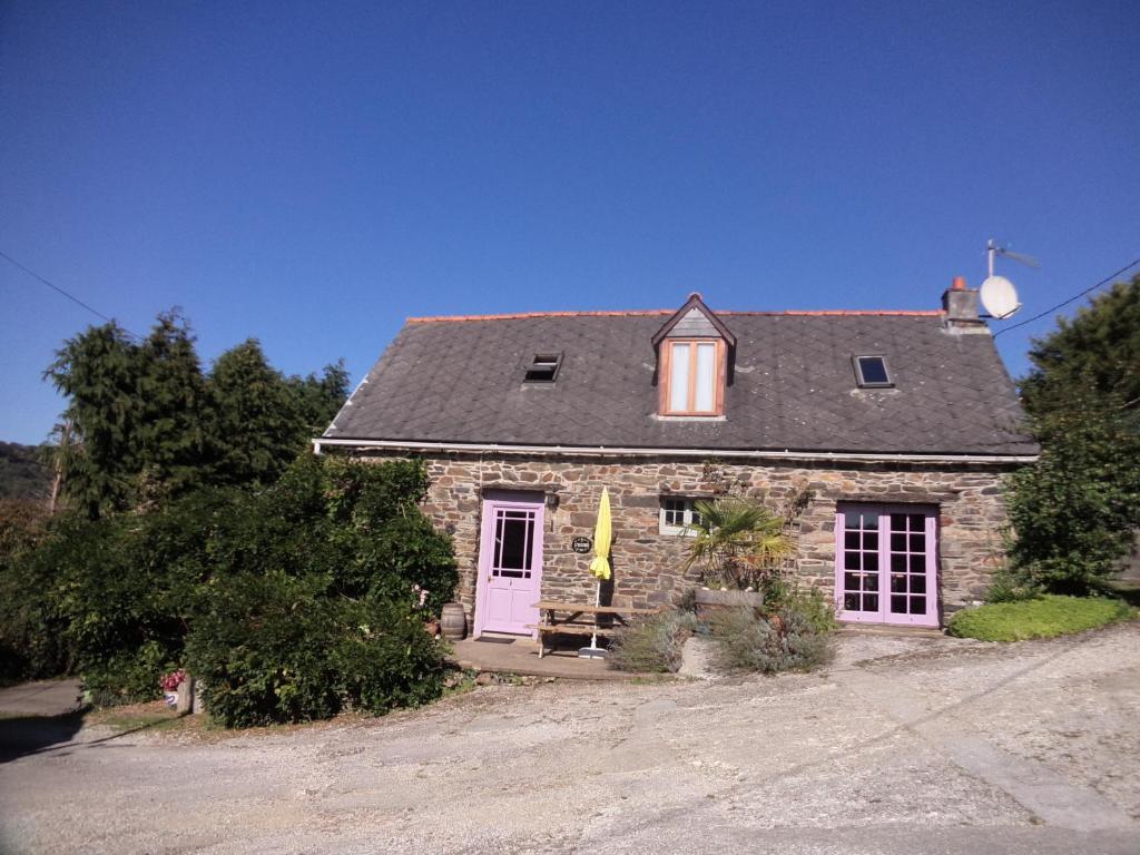 una pequeña casa de piedra con puerta rosa en L'Ecurie at Rest Huella en Saint-Ségal