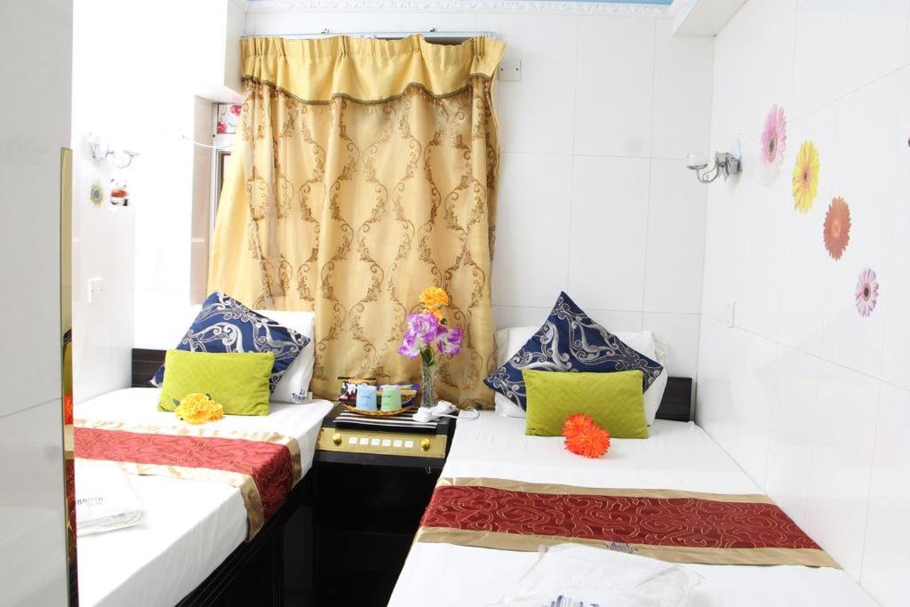2 camas en una habitación pequeña con almohadas amarillas y azules en Pay-Less Guesthouse (7/F A9), en Hong Kong