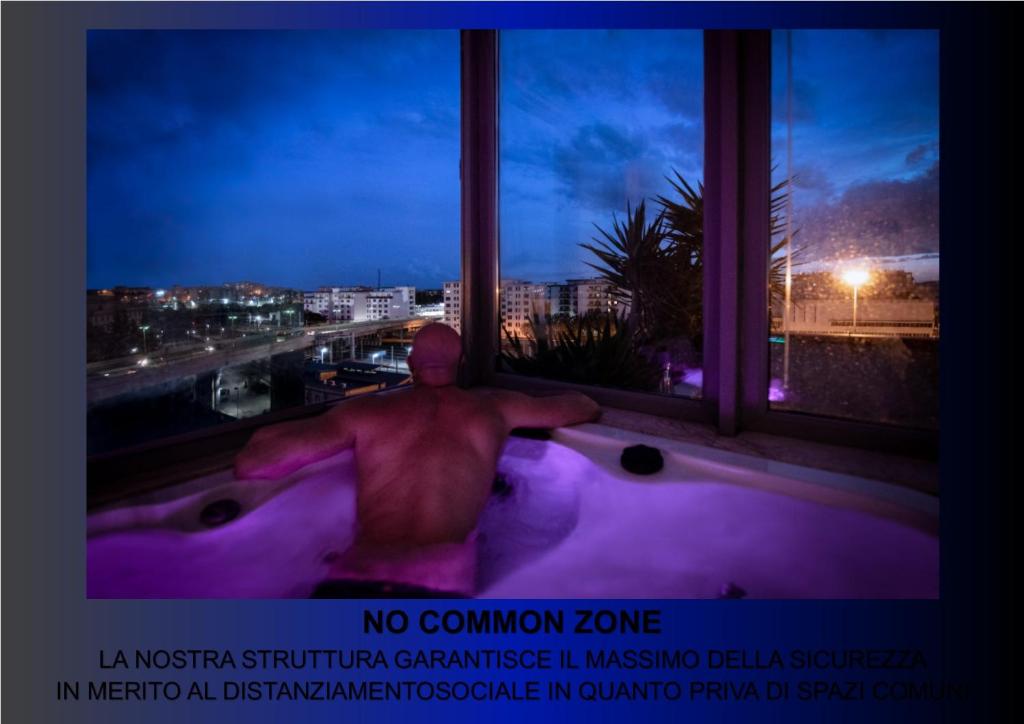 Ein Mann, der in einer Badewanne sitzt und aus dem Fenster schaut. in der Unterkunft Penthouse Station Luxury Suites & Apartment in Brindisi