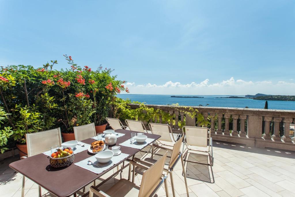 a table and chairs on a patio with a view of the ocean at Alloro in Gardone Riviera