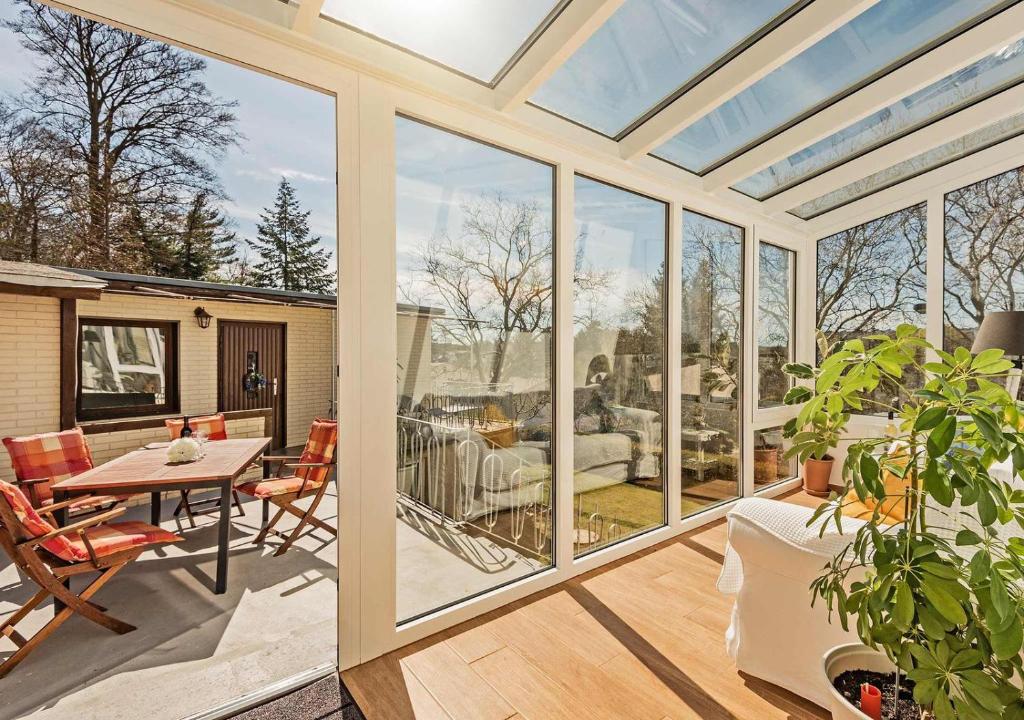 un salón acristalado con mesa, sillas y ventanas de cristal en Ferienhaus Ingrid en Heringsdorf