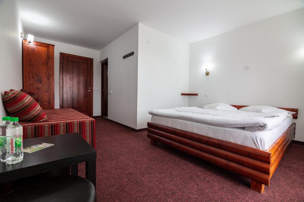 ブルトプにあるPensiunea Piatra Graitoareのベッドとソファ付きのホテルルーム