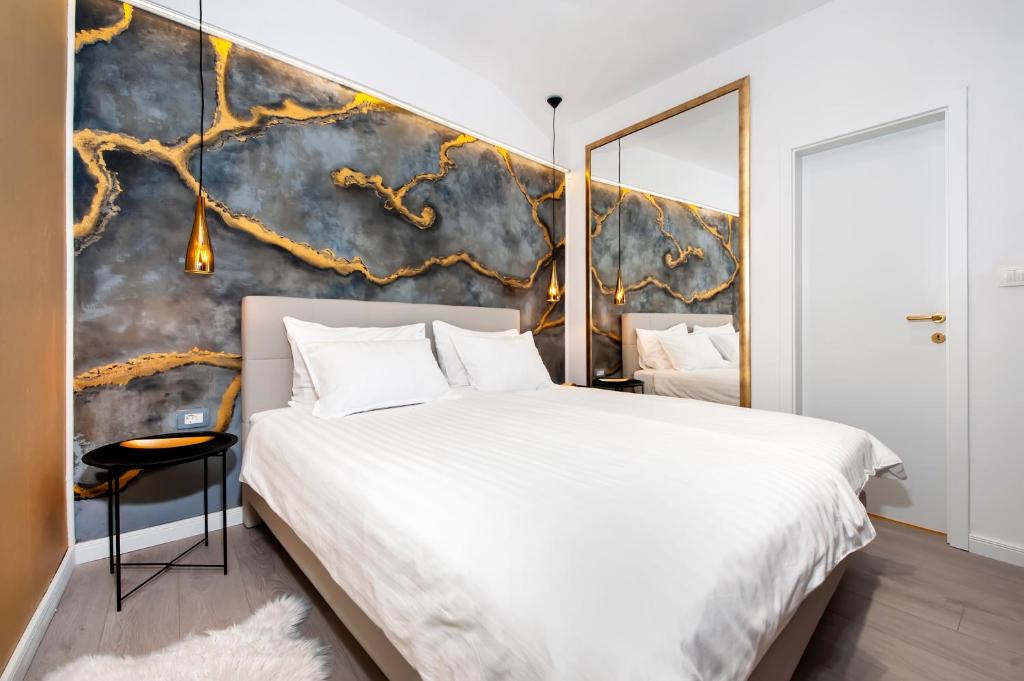 a bedroom with a large white bed and a wall at Deluxe Studio G 12 in Rovinj