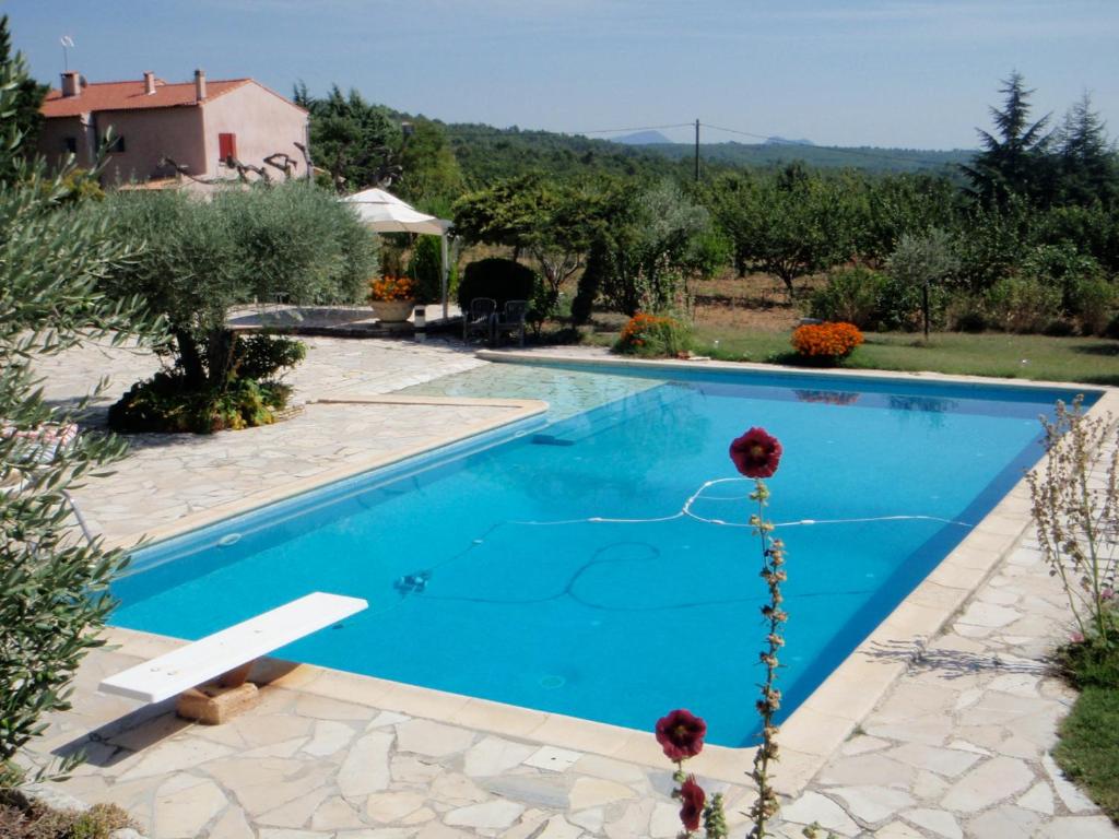 a swimming pool in a garden with a house at Gîte Anaïs in La Verdière