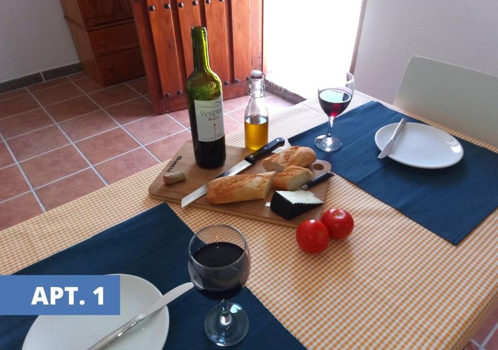 uma mesa com uma garrafa de vinho e pão e copos de vinho em Casa la Cabra em Moclín