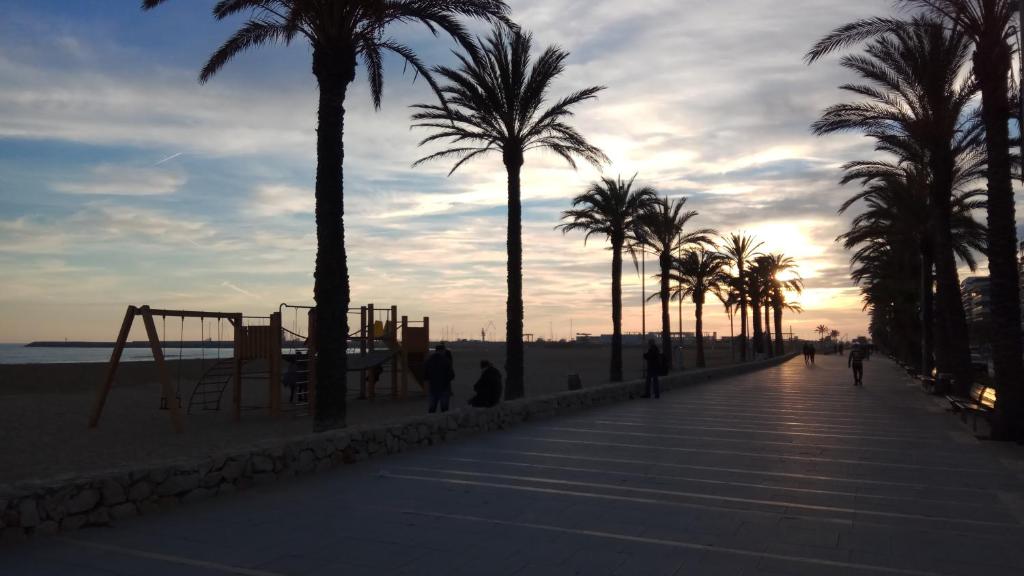 un paseo marítimo con palmeras y un parque infantil en la playa en Segur Beach, en Segur de Calafell