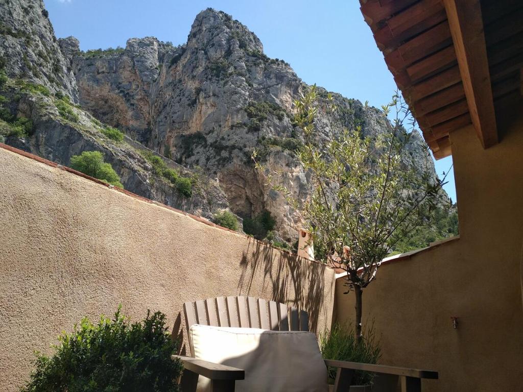 uma cadeira sentada em frente a uma parede com uma montanha em La Maison de Moustiers em Moustiers-Sainte-Marie