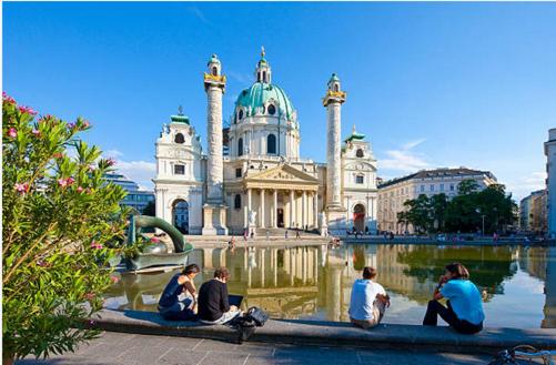 een groep mensen die op een boomstam voor een gebouw zitten bij Operngasse-Karlsplatz in Wenen