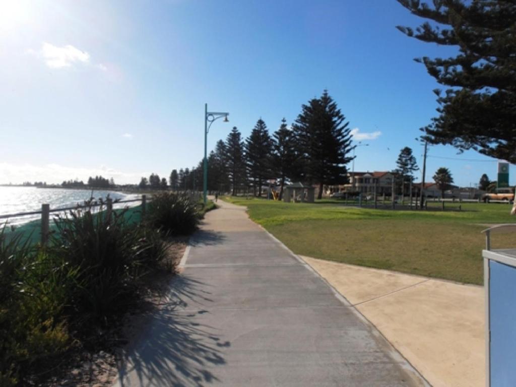 a sidewalk next to a park next to a body of water at Warnbro Beach Family Accommodation in Warnbro