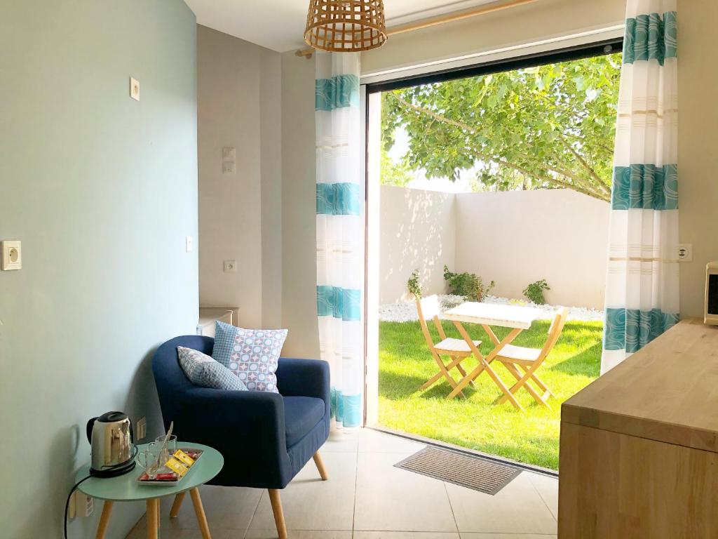 uma sala de estar com uma cadeira azul e uma porta de vidro deslizante em Estrella em Les Sables-dʼOlonne