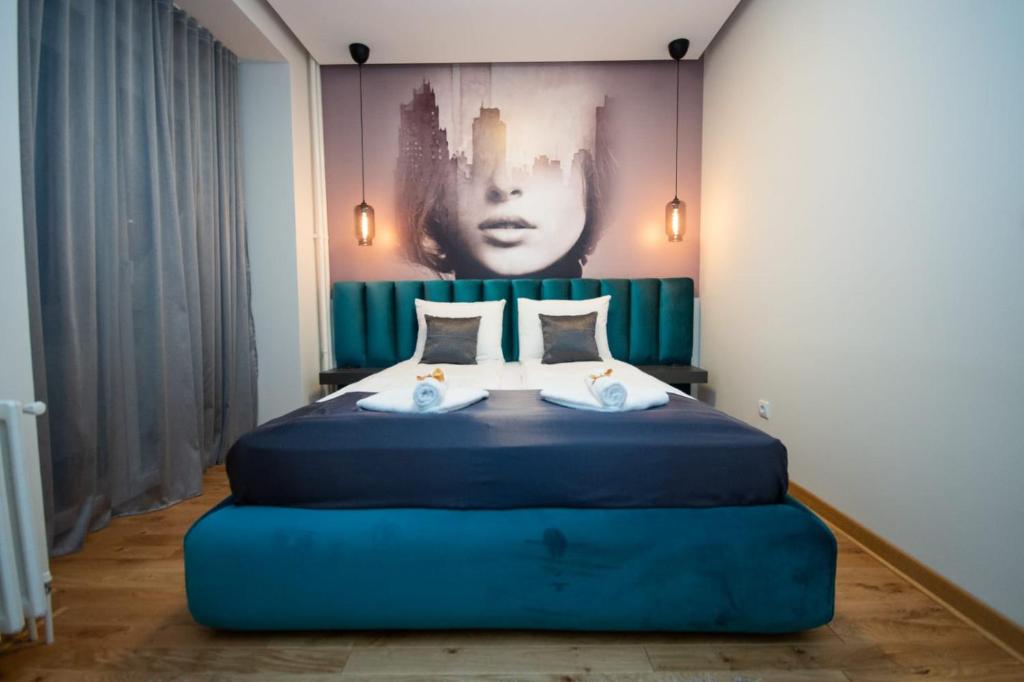 a bedroom with a blue bed with a painting on the wall at Belgrade CITY CENTER Apartments in Belgrade